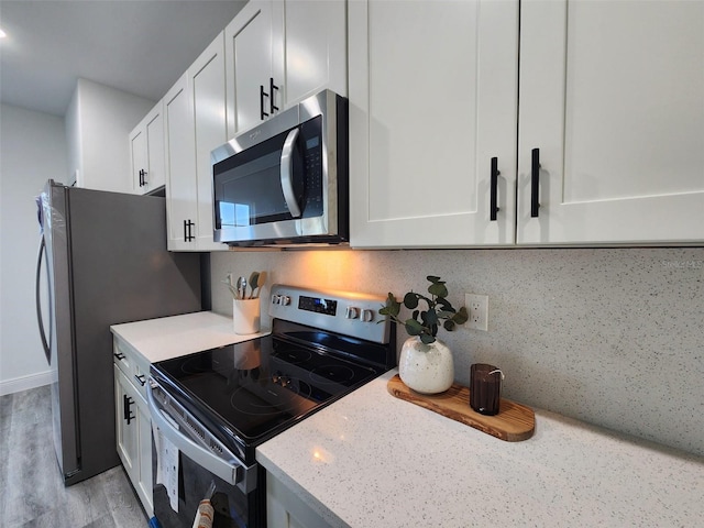 kitchen featuring light stone counters, appliances with stainless steel finishes, backsplash, and white cabinetry