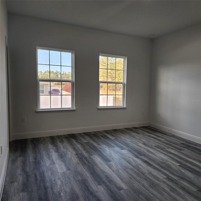 unfurnished room with dark wood-type flooring and baseboards