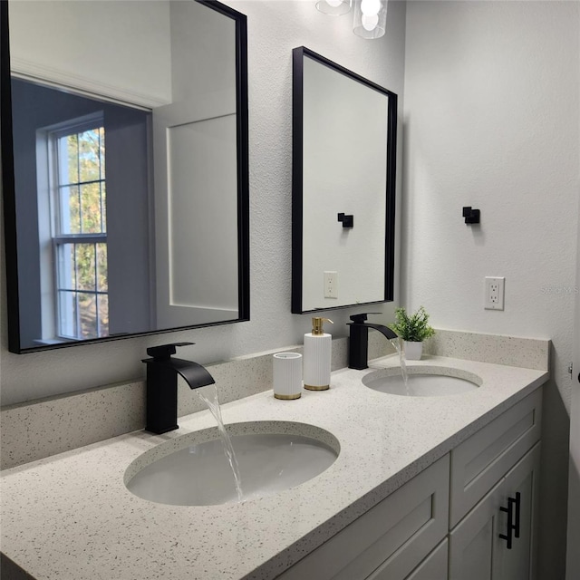 bathroom featuring double vanity, a sink, and a textured wall