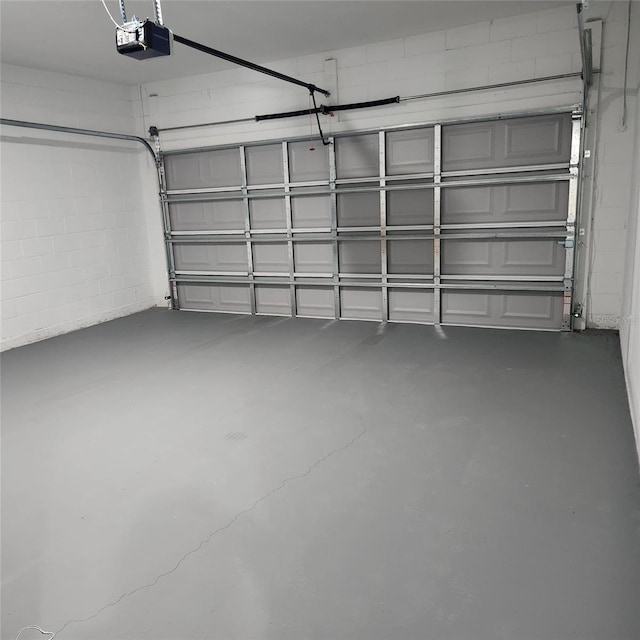 garage with a garage door opener and concrete block wall