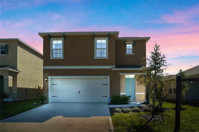 view of front of home featuring driveway, an attached garage, and stucco siding