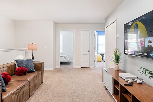 living area featuring baseboards and light colored carpet