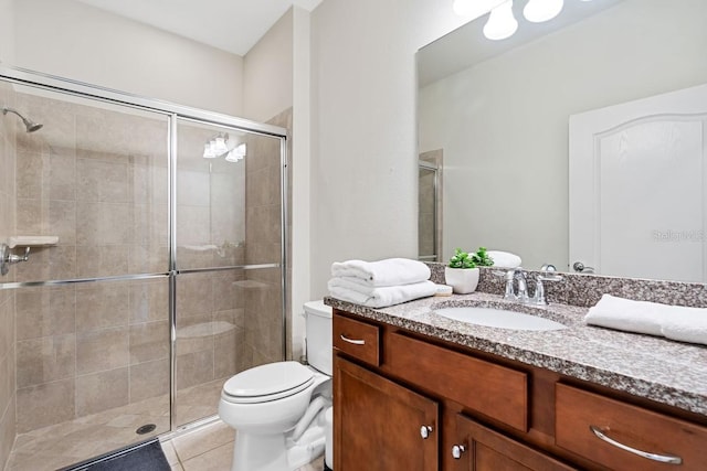 bathroom featuring toilet, a shower stall, vanity, and tile patterned floors