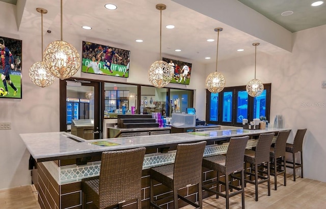 bar featuring light wood-type flooring, hanging light fixtures, and recessed lighting