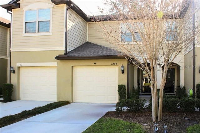 multi unit property with concrete driveway, roof with shingles, an attached garage, and stucco siding