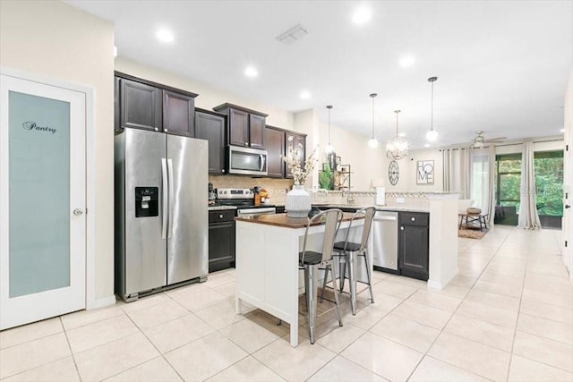 kitchen featuring a breakfast bar area, stainless steel appliances, a peninsula, visible vents, and backsplash