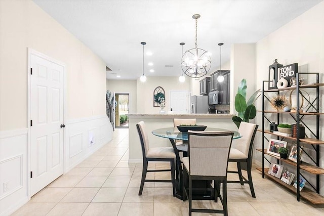 dining space with a chandelier, a wainscoted wall, a decorative wall, and light tile patterned floors