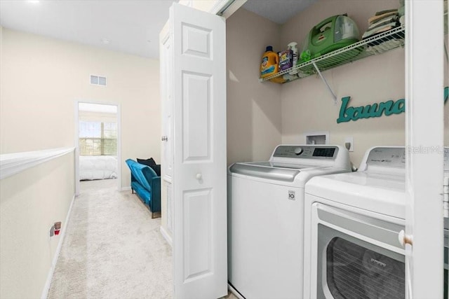 washroom featuring light colored carpet, laundry area, visible vents, baseboards, and washer and clothes dryer