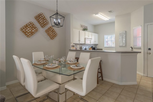 dining room with a chandelier, light tile patterned flooring, visible vents, and baseboards