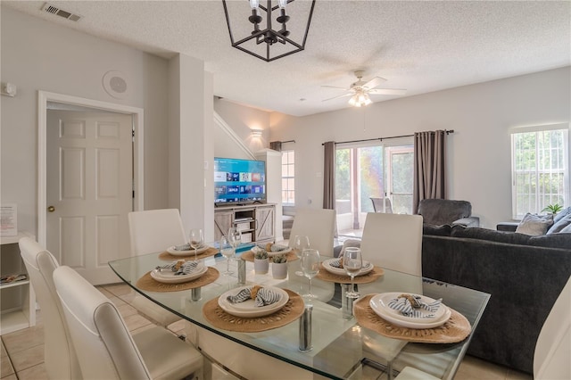 dining space with a textured ceiling, light tile patterned floors, visible vents, and a ceiling fan