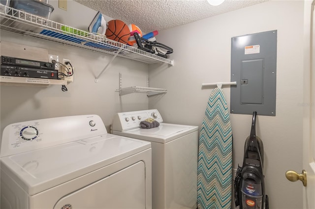 washroom with a textured ceiling, laundry area, separate washer and dryer, and electric panel