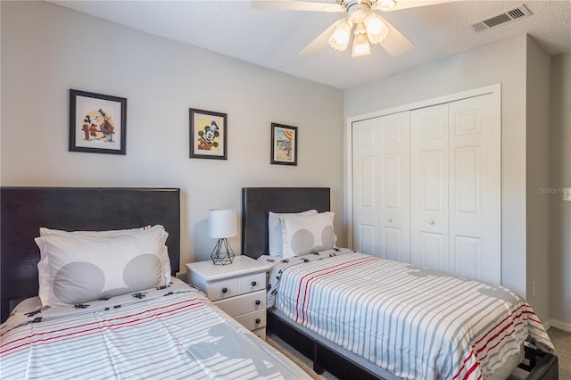 bedroom with carpet floors, a closet, visible vents, a ceiling fan, and a textured ceiling