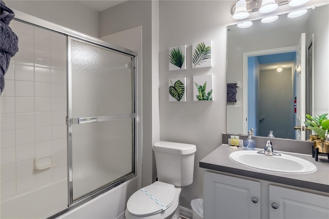 full bath with toilet, bath / shower combo with glass door, and vanity