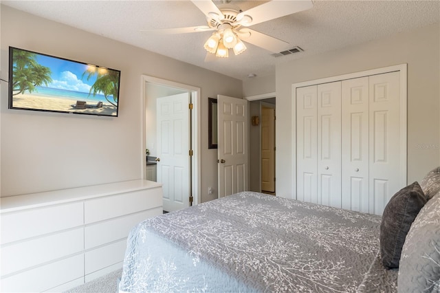 bedroom with a textured ceiling, a closet, visible vents, and a ceiling fan