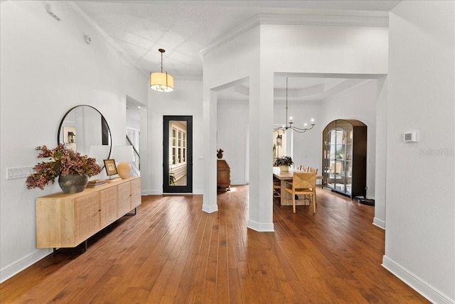 entryway featuring ornamental molding, arched walkways, baseboards, and hardwood / wood-style floors