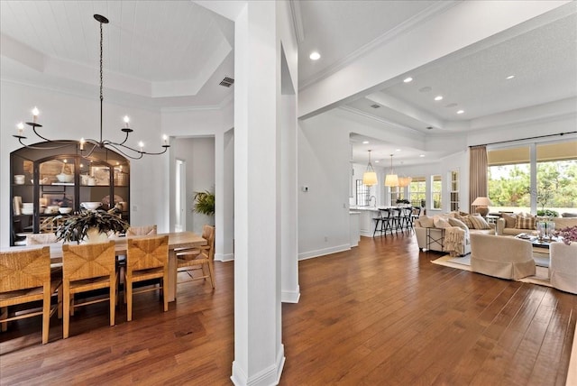 dining space featuring wood-type flooring, a chandelier, and a raised ceiling