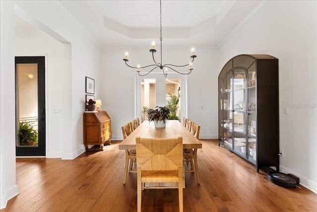 dining area featuring baseboards, a raised ceiling, and hardwood / wood-style floors