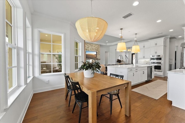 dining room with dark wood-style floors, baseboards, visible vents, and crown molding