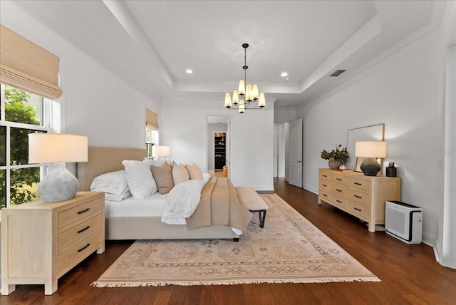 bedroom with dark wood-style floors, a raised ceiling, multiple windows, and a notable chandelier