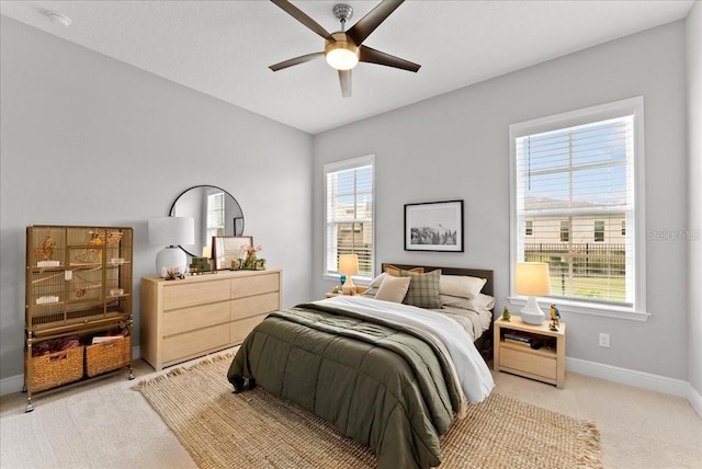 bedroom with a ceiling fan, light colored carpet, and baseboards