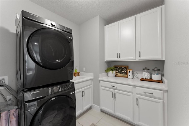 clothes washing area with stacked washer and clothes dryer, cabinet space, a textured ceiling, and light tile patterned floors