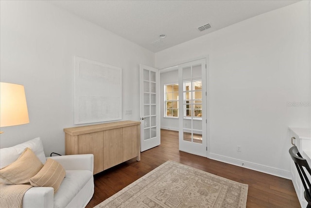 living area with baseboards, dark wood-type flooring, and french doors