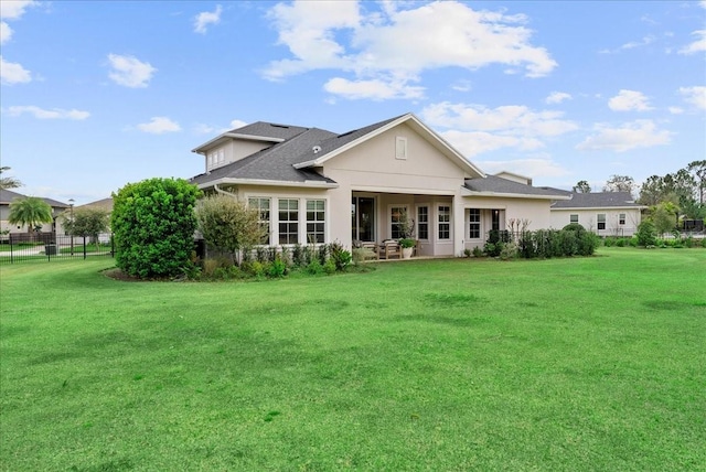 back of house featuring a shingled roof, a lawn, and fence