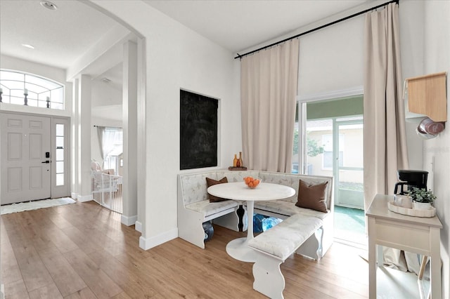 dining space featuring baseboards, breakfast area, arched walkways, and wood finished floors