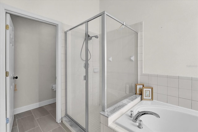 bathroom featuring baseboards, a stall shower, a garden tub, and tile patterned floors