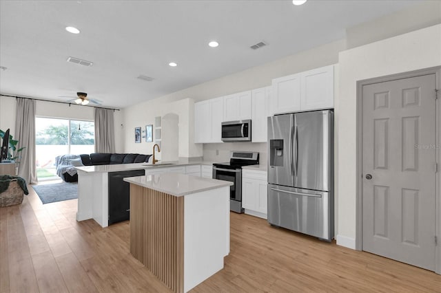 kitchen featuring stainless steel appliances, a kitchen island, a sink, visible vents, and open floor plan