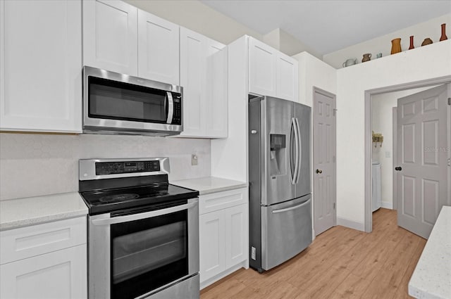 kitchen featuring tasteful backsplash, appliances with stainless steel finishes, light wood-style floors, white cabinetry, and baseboards