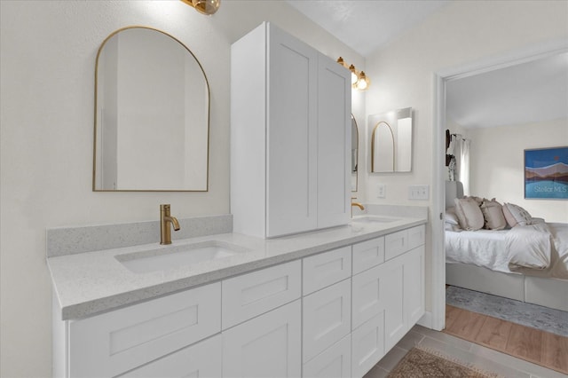 ensuite bathroom featuring double vanity, a sink, and connected bathroom