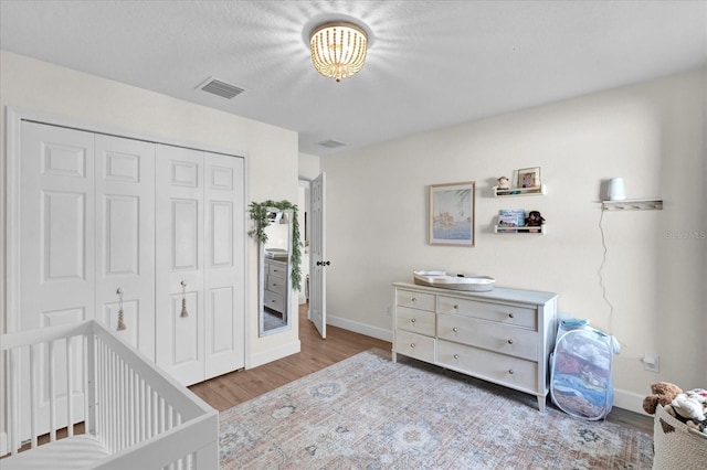 bedroom with a closet, visible vents, baseboards, and wood finished floors