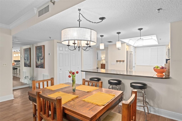 dining space with visible vents, a textured ceiling, and wood finished floors