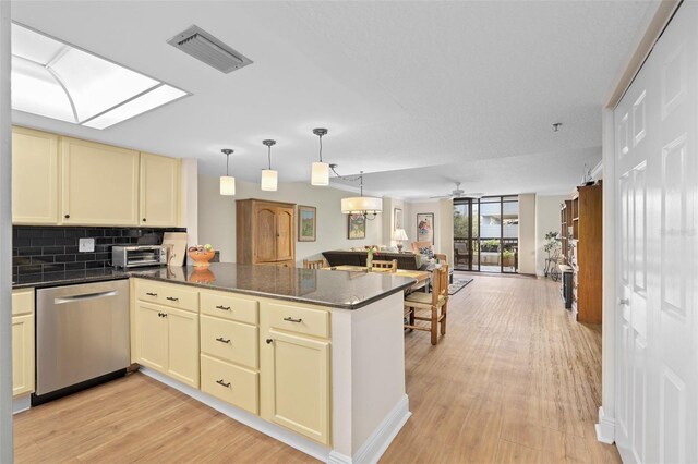 kitchen with visible vents, cream cabinets, stainless steel dishwasher, open floor plan, and a peninsula