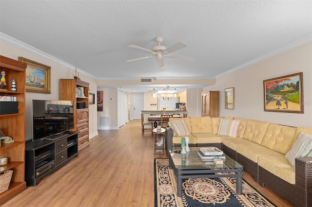 living room with light wood finished floors, a textured ceiling, visible vents, and crown molding