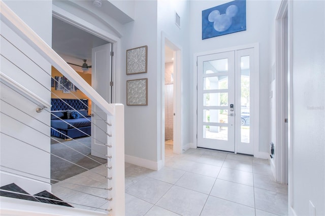 tiled foyer entrance with ceiling fan, stairway, visible vents, and baseboards