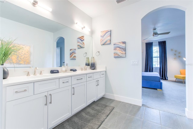 full bath featuring double vanity, baseboards, a ceiling fan, ensuite bathroom, and a sink