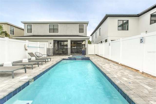 back of house featuring a patio, a fenced backyard, a pool with connected hot tub, and stucco siding