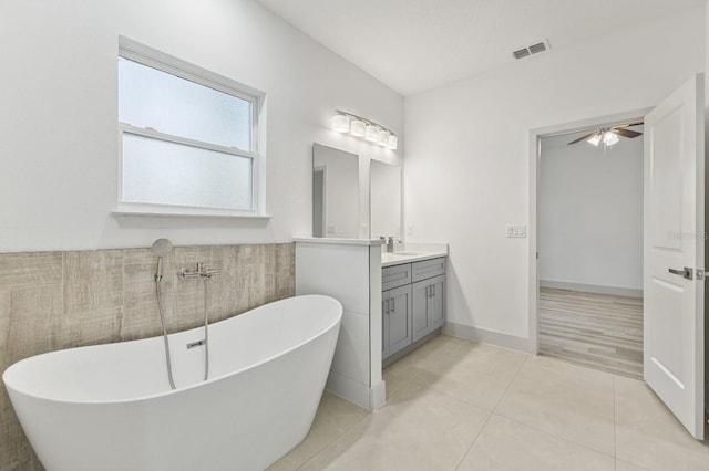 bathroom with visible vents, a freestanding bath, vanity, baseboards, and tile patterned floors