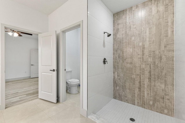 full bathroom with ceiling fan, tile patterned flooring, a tile shower, and toilet