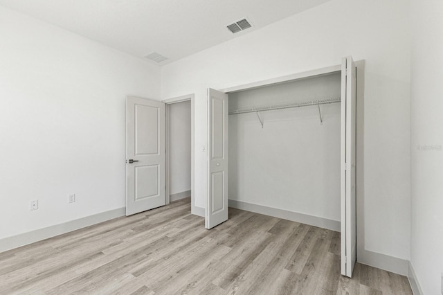 unfurnished bedroom featuring a closet, visible vents, baseboards, and wood finished floors