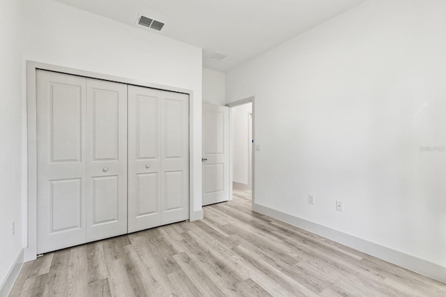 unfurnished bedroom with light wood-style floors, a closet, visible vents, and baseboards