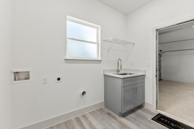 clothes washing area with washer hookup, a sink, electric dryer hookup, light wood-type flooring, and baseboards