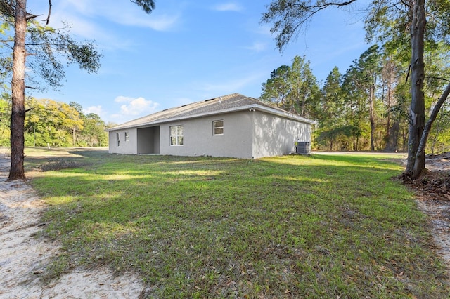 view of side of home with central AC, a lawn, and stucco siding