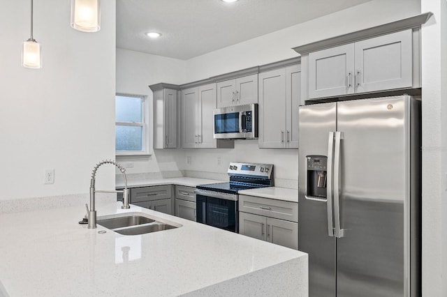 kitchen featuring stainless steel appliances, hanging light fixtures, gray cabinetry, a sink, and a peninsula