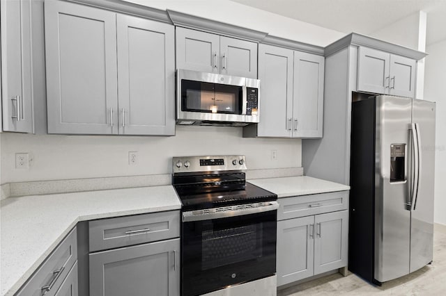 kitchen with light wood-type flooring, gray cabinets, and stainless steel appliances