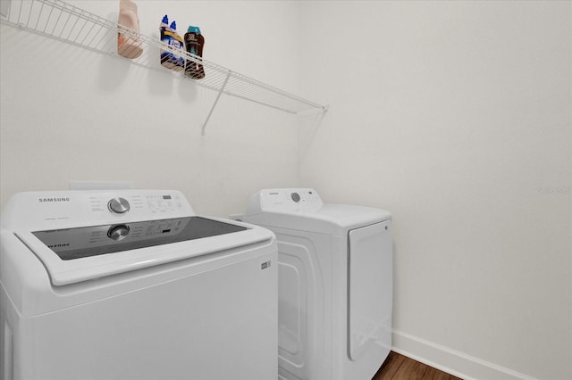clothes washing area with baseboards, laundry area, dark wood-style floors, and washing machine and dryer