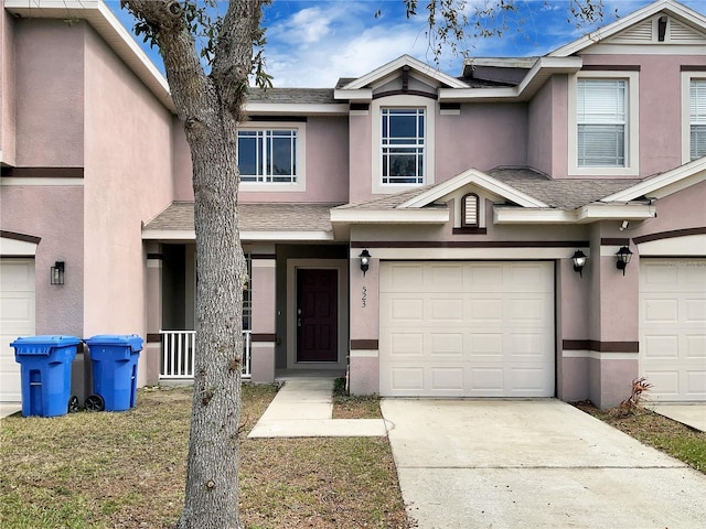 view of front of home featuring driveway, roof with shingles, and stucco siding