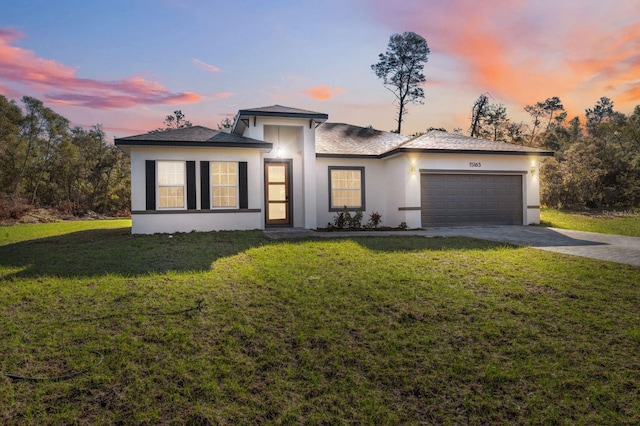 view of front of property with a garage, driveway, a yard, and stucco siding